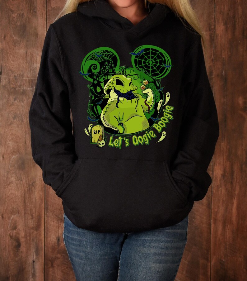 May include: Black hooded sweatshirt featuring a green graphic of Oogie Boogie from The Nightmare Before Christmas. The design includes a Mickey Mouse ear silhouette, a haunted house, and the text "Let's Oogie Boogie".