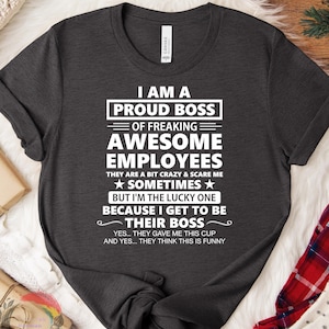 May include: Dark heather gray t-shirt with the text "I AM A PROUD BOSS OF FREAKING AWESOME EMPLOYEES." The shirt also includes the text "THEY ARE A BIT CRAZY & SCARE ME" and "BUT I'M THE LUCKY ONE BECAUSE I GET TO BE THEIR BOSS."