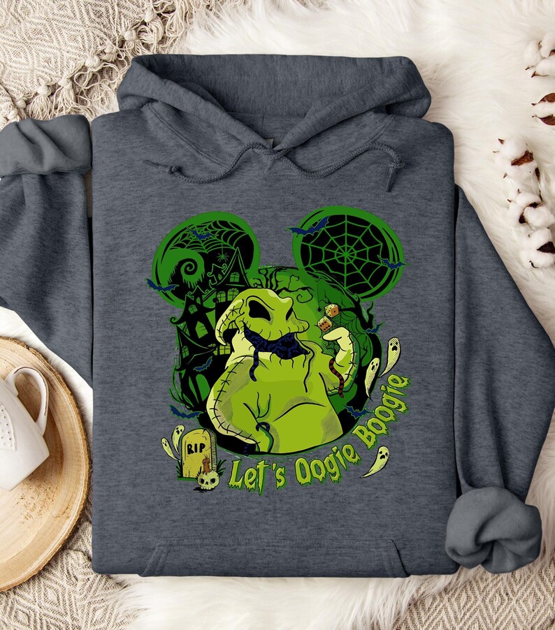 May include: Dark gray hooded sweatshirt featuring a green Oogie Boogie design with a haunted house, bats, and spiderwebs. The text "Let's Oogie Boogie" is printed in green. The design is in the shape of Mickey Mouse ears.