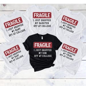 May include: White and black t-shirts with the word "FRAGILE" in a red rectangle, and the phrases "I JUST DROPPED MY BABY OFF AT COLLEGE", "I JUST DROPPED MY DAUGHTER OFF AT COLLEGE", "I JUST DROPPED MY TWINS OFF AT COLLEGE", and "I JUST DROPPED MY SON OFF AT COLLEGE".
