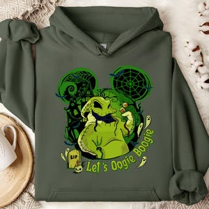 May include: Dark green hoodie featuring a graphic of Oogie Boogie from The Nightmare Before Christmas. The design includes a green Oogie Boogie, bats, ghosts, and the text "Let's Oogie Boogie". The design is set against a green Mickey Mouse silhouette.