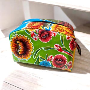Könnte beinhalten: Eine Kosmetiktasche mit floralem Muster in Grün, Blau und Gelb mit Reißverschluss.