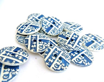 May include: A pile of blue and white ceramic buttons with a floral pattern. The buttons are round and have two holes.