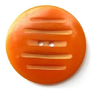 May include: A round, orange button with horizontal grooves and two small holes for sewing. The button is a solid color and has a slightly textured surface. The button is a vintage style and is likely made of plastic.