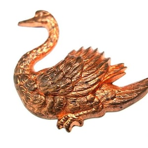 Könnte beinhalten: Eine kupferfarbene Schwanenfigur mit detaillierten Federn und einem geschwungenen Hals. Der Schwan befindet sich in einer Ruheposition mit ausgebreiteten Flügeln.