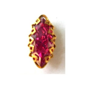 Puede incluir: Un engaste dorado con una piedra preciosa rosa oscuro en forma de marquesa.