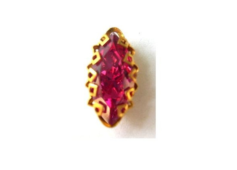 Puede incluir: Un engaste dorado con una piedra preciosa rosa oscuro en forma de marquesa.