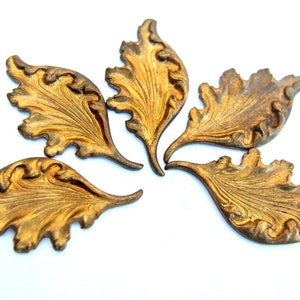 May include: Five gold-colored metal leaf-shaped embellishments with intricate swirling designs.