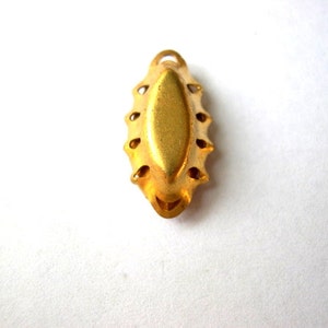 Puede incluir: Pendiente de metal dorado con un borde decorativo festoneado y un centro liso de forma ovalada.