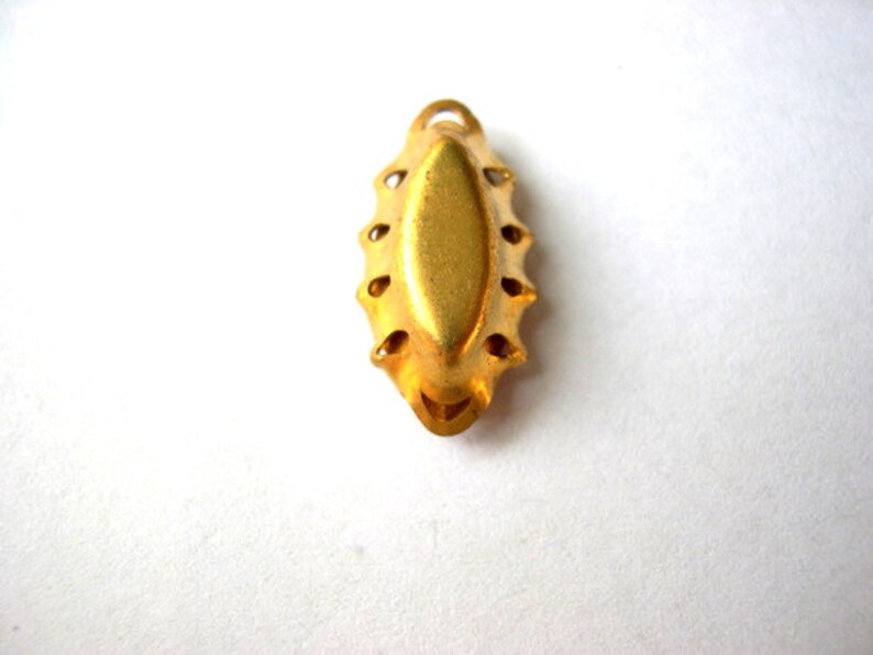 Puede incluir: Pendiente de metal dorado con un borde decorativo festoneado y un centro liso de forma ovalada.