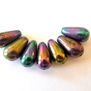May include: Seven iridescent teardrop-shaped glass beads in shades of purple, green, and gold.