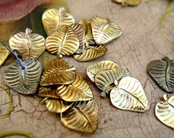 May include: A collection of gold-toned metal leaf charms. The leaves have a detailed, textured design and are perfect for jewelry making or crafting projects.