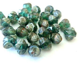 Può includere: Una collezione di perline di vetro verde con un design sfaccettato. Le perline hanno una finitura testurizzata e iridescente.