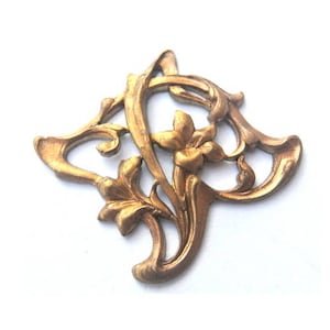Può includere: Pezzo decorativo in metallo dorato con un design floreale. Il pezzo ha la forma di un fiore stilizzato con dettagli intricati.