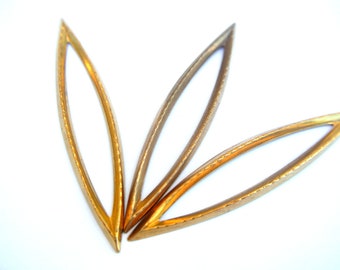 May include: Three gold-colored metal needle threaders, each with a pointed tip and a slightly curved shape.