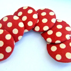 May include: Six red fabric buttons with white polka dots arranged in a semi-circle.