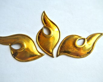 May include: Three gold-colored metal decorative pieces shaped like stylized leaves with a hole in the center of each piece.