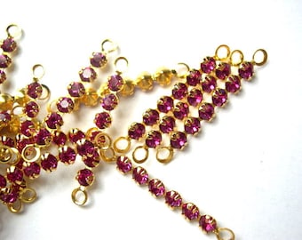 May include: A strand of pink rhinestone chain with gold-toned connectors. The chain is made up of small, round rhinestones that are set in a gold-toned metal setting. The chain is perfect for adding a touch of sparkle to any project.