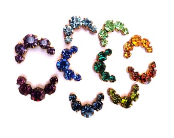 May include: Assortment of crescent-shaped rhinestone embellishments in various colors, including purple, blue, green, and orange.