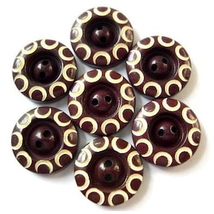 May include: Eight brown buttons with a white crescent moon pattern. The buttons have two holes each.