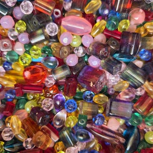 Peut inclure: Un grand assortiment de perles de verre colorées de formes et de tailles variées. Les perles sont un mélange de couleurs opaques et translucides, notamment le rouge, le bleu, le vert, le jaune, le rose et le violet.