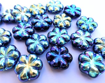 Puede incluir: Un conjunto de cuentas iridiscentes azules con forma de flor. Las cuentas tienen un acabado brillante y un brillo multicolor, que refleja tonos de azul, morado y dorado. Estas cuentas decorativas son ideales para la fabricación de joyas y proyectos de artesanía.