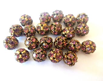 May include: A group of 20 round beads with a gold metal finish and a purple rhinestone design.