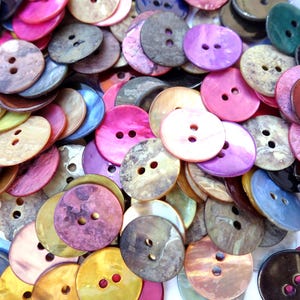 May include: A large collection of colourful, round, two-hole buttons made from mother of pearl. The buttons are in various shades of pink, purple, blue, green, brown, and white.