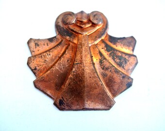 May include: A copper-colored metal ornament with a geometric design. The ornament has a heart shape at the top and a fan-shaped design at the bottom.