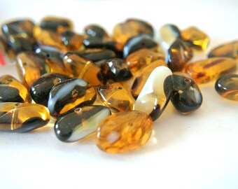May include: A pile of brown and black glass beads with white swirls. The beads are oval shaped and have a glossy finish.