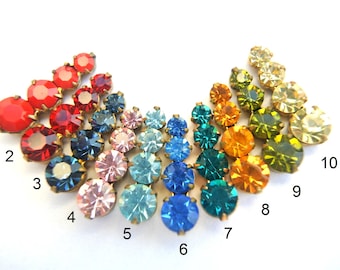May include: A rainbow assortment of 10 different colored rhinestones, each with a gold setting. The rhinestones are arranged in a semi-circle shape, with the colors transitioning from red to yellow.