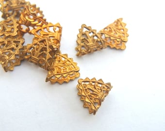 May include: A group of gold metal decorative trim pieces with a filigree design. The pieces are shaped like triangles and have a delicate, intricate pattern.