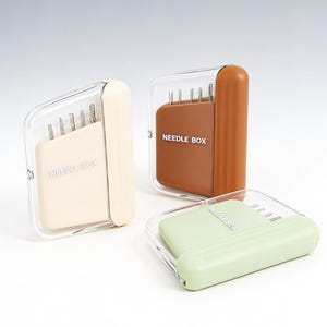 Peut inclure: Trois boîtes à aiguilles de couleurs crème, marron et vert clair. Chaque boîte a un couvercle en plastique transparent et l'inscription "NEEDLE BOX" imprimée sur le devant. Les boîtes sont conçues pour contenir des aiguilles.