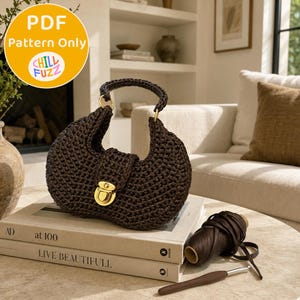 May include: A dark brown crocheted handbag with a crescent shape, a single top handle, and a gold-toned metal clasp closure. Next to the bag sits a spool of dark brown yarn and a crochet hook. The image includes a circular label reading PDF Pattern Only.