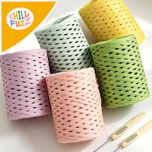 May include: A collection of colorful spools of woven paper twine in shades of pink, green, yellow, and peach. Two crochet hooks are visible. The logo "CHILL FUZZ" is in the upper left corner.