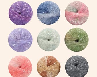 Puede incluir: Nueve ovillos de lana colorida en una variedad de colores, incluyendo morado, azul, rosa, lavanda, verde, naranja, beige y gris. Cada ovillo está salpicado de puntos blancos, y la lana parece suave y esponjosa. La lana está dispuesta en un patrón de cuadrícula.
