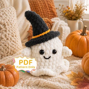 May include: A white crocheted ghost plushie wearing a black witch hat with an orange band. The ghost has two black plastic eyes and a stitched black smile. A white label with a colourful border displays the text PDF Pattern Only.