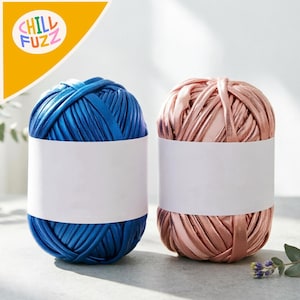 May include: Two skeins of yarn, one in a vibrant blue and the other in a soft rose color. Each skein is neatly wound and presented with a blank white label. The upper left corner features the text "CHILL FUZZ" in a playful font.