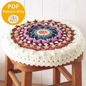 May include: A round, multi-colored crochet stool cover with a detailed, circular design. The cover features a variety of colors, including blue, purple, red, and green, with a white border. The text "PDF Pattern Only" and "Chill Fuzz" are in the upper left corner.