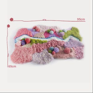K&ouml;nnte beinhalten: Ein farbenfroher, abstrakter Teppich mit einem strukturierten, weichen Design. Der Teppich zeigt verschiedene Rosa-, Lila-, Gr&uuml;n- und Blaut&ouml;ne mit einer Mischung aus flauschigen und unebenen Texturen. Er ist etwa 65 cm breit und 95 cm lang.