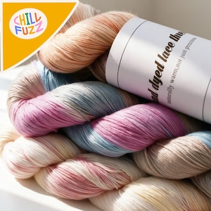 May include: A skein of hand-dyed lace thread in a variety of pastel colors, including pink, blue, beige, and cream. The yarn is tightly wound and appears soft. A white label with text is visible. The logo "Chill Fuzz" is in the upper left corner.