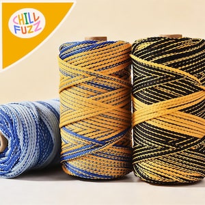Op de afbeelding: Close-up van drie spoelen kleurrijk koord. Eén spoel is blauw en wit, een andere is geel en blauw, en de derde is geel en zwart. De spoelen zijn strak gewikkeld en hebben een textuur. Het logo "CHILL FUZZ" staat in de linkerbovenhoek.