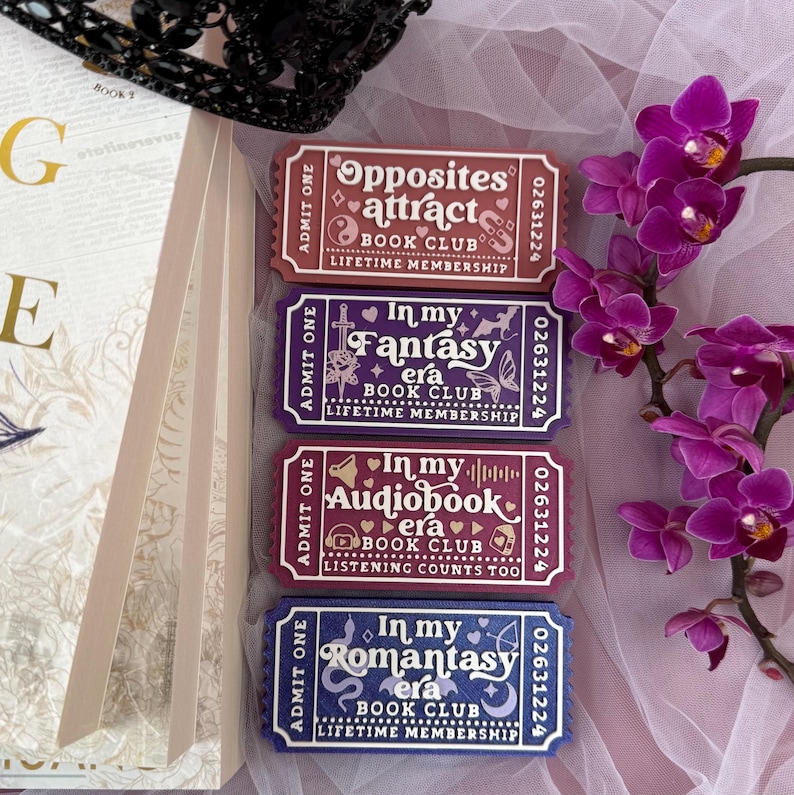 K&ouml;nnte beinhalten: Vier rechteckige Mitgliedskarten f&uuml;r den Buchclub in Lila-, Rot- und Blaut&ouml;nen mit wei&szlig;em Text. Die Tickets tragen S&auml;tze wie "Opposites Attract" und "In My Fantasy Era". Ein Zweig lila Orchideen und ein Buch sind im Hintergrund.