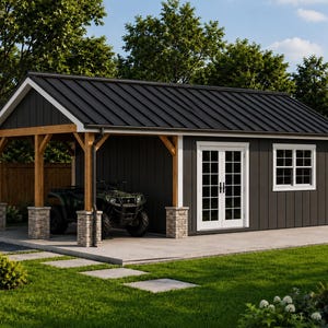 Op de afbeelding: Een donkergrijze schuur met een zwart metalen dak, witomlijnde dubbele glazen deuren en een raam. De structuur heeft een open carportgedeelte ondersteund door houten balken en met steen beklede pilaren, met daarin een donkergroene quad.