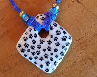 Paw prints on a fused glass pendant with a leather cord necklace.