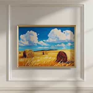 Op de afbeelding: Een ingelijst landschapsschilderij toont een zonnig veld met hooibalen onder een helderblauwe lucht vol pluizige witte wolken. Het kunstwerk is ingelijst in een goudkleurige lijst, wat een vleugje elegantie toevoegt aan de landelijke scène.