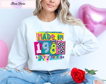 Puede incluir: Sudadera blanca con un diseño gráfico colorido que dice "Made in 1985 Limited Edition".