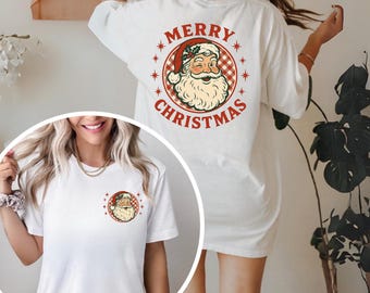 May include: White t-shirt with a circular graphic of Santa Claus and the text "MERRY CHRISTMAS" in red. The Santa graphic is repeated on the front and back of the shirt. The Santa graphic is in a red and white checkered circle.