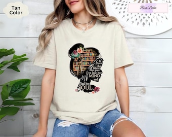 May include: Tan colored t-shirt with a graphic of a woman's silhouette with bookshelves for hair. The text reads "& into the library she goes to lose her MIND and find her SOUL."