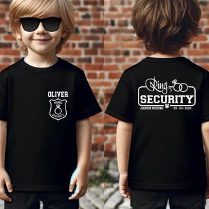 May include: Black t-shirt with white text that says "Ring Security" and "Oliver" with a ring and shield graphic. The back of the shirt says "Ring Security" with two rings and the text "Johnson Wedding 04-04-2024".